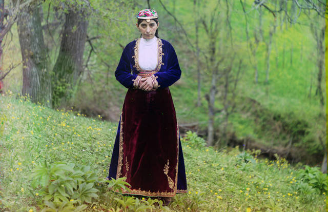 An Armenian woman in national costume poses for Prokudin-Gorskii on a hillside near Artvin (in present day Turkey), circa 1910